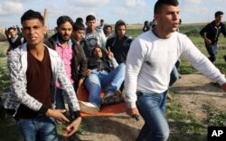 Palestinian protesters evacuate a wounded person during clashes with Israeli troops on the Israeli border with Gaza, east of Gaza City, March 16, 2018.