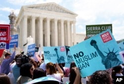 Protesters hold up signs and call out against the Supreme Court ruling upholding President Donald Trump's travel ban outside the the Supreme Court in Washington, June 26, 2018.
