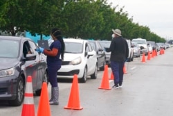 Employees of Nomi Health check in a long line of people for COVID-19 tests, in North Miami, Fla., Dec. 21, 2021.