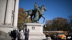 Visitors to the American Museum of Natural History in New York look at a statue of Theodore Roosevelt, flanked by a Native American man and African American man, Nov. 17, 2017.