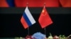 Bendera Rusia, kiri, dan China diletakkan di atas meja sebelum upacara penandatanganan di Aula Besar Rakyat di Beijing, Jumat, 8 Juni 2018. (Foto: AP)