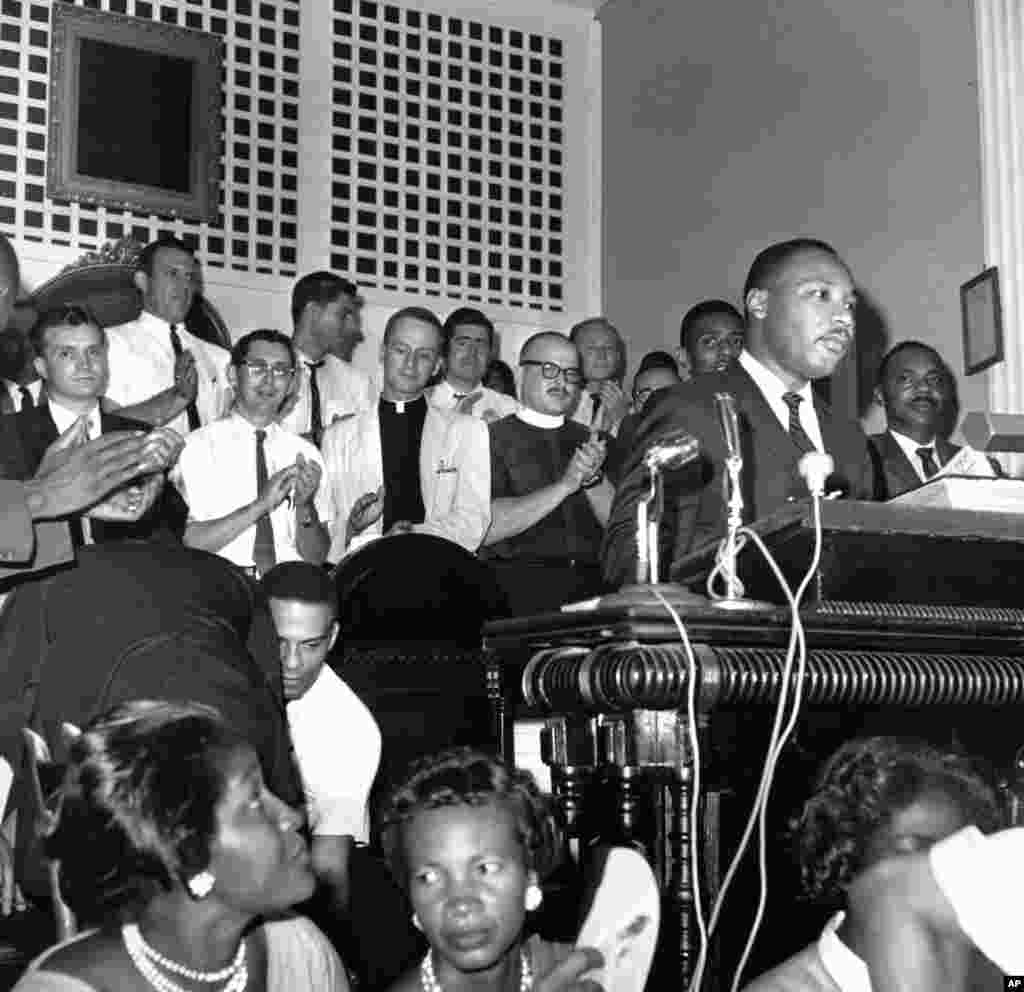 1962 - Wasu malaman addini daga jihohin arewa su na tafa ma shugaban majalisar shugabannin coci-coci na jihohin kudu,m Martin Luther King Jr. a lokacin da yake jawabi cikin wata majami&#39;a a Albany, Jihar Georgia a ranar 28 Agusta, 1962.