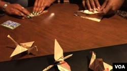 Mya Brown and Dominic Green participate in the 2,300 paper cranes folding event​ at Radical Library inside Eaton DC, Washington DC, on November 18, 2018. (Say Mony/VOA Khmer) 