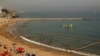 Des gens profitent de la plage alors que la police patrouillent, dans le détroit de Gibraltar, le 10 août 2015.