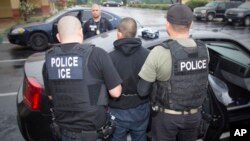 FILE - photo released by U.S. Immigration and Customs Enforcement shows foreign nationals being arrested this week during a targeted enforcement operation conducted by U.S. Immigration and Customs Enforcement (ICE).
