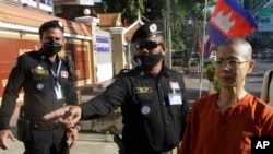 Court securities direct Cambodian-American lawyer Theary Seng, right, dressed in a prison-style orange outfit, to the entrance of Phnom Penh Municipal Court in Phnom Penh, Cambodia, Tuesday, Jan. 4, 2022. (AP Photo/Heng Sinith)