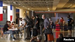 Pengunjung mengantre untuk mendaftarkan dokumennya kepada petugas kedutaan Prancis sebelum penerbangan carteran mereka kembali ke negara mereka, di tengah penyebaran COVID-19, di Bandara Internasional Ngurah Rai di Bali, 28 Maret 2020. (Foto: Reuters)
