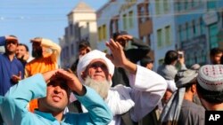 People look up at a dead body hanged by the Taliban from a crane in the main square of Herat city in western Afghanistan, Sept. 25, 2021.