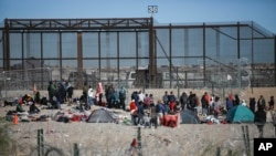Migrants line up at the U.S. border wall after being detained by U.S. immigration authorities, seen from Ciudad Juarez, Mexico, Dec. 27, 2023. 