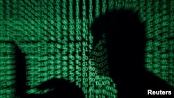 Seorang pria di depan laptop dengan latar kode-kode siber dalam foto ilustrasi, 13 Maei 2017.