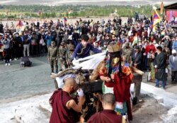 FILE - A relative places khadaks, a white piece of silk cloth, over the pyre of Nyima Tenzin, a senior Tibetan official from India's Special Frontier Force, during his cremation ceremony in Leh, Sept. 7, 2020.