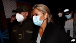 FILE - Bolivia's former interim president, Jeanine Áñez, who has been detained, is escorted Bolivian Police Commander Jhonny Aguilera at the military airport in El Alto, Bolivia, March 13, 2021.