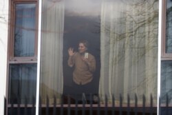 Zari Tadayon gestures from a window of the Radisson Blu Hotel at Heathrow Airport, as Britain introduces hotel quarantine programme for arrivals from a 'red list' of 30 countries, in London, Britain, Feb. 15, 2021.