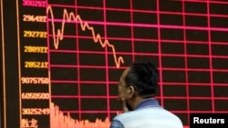 Seorang investor mengamati monitor yang menyajikan informasi indeks bursa saham Shanghai di Beijing (26/8). 