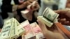 Seorang pegawai valas menghitung uang kertas dollar AS dan rupiah, di Makassar, Sulawesi Selatan, 31 Januari 2013. (Foto: Yusuf Ahmad/Reuters)