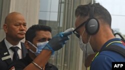 Seorang petugas memeriksa suhu tubuh atlet kriket Faf du Plessis (kanan) setibanya di Kolkata, India, 16 Maret 2020. Afrika Selatan mendeklarasikan wabah virus corona (COVID-19) sebagai bencana keamanan nasional, Minggu (15/3).
