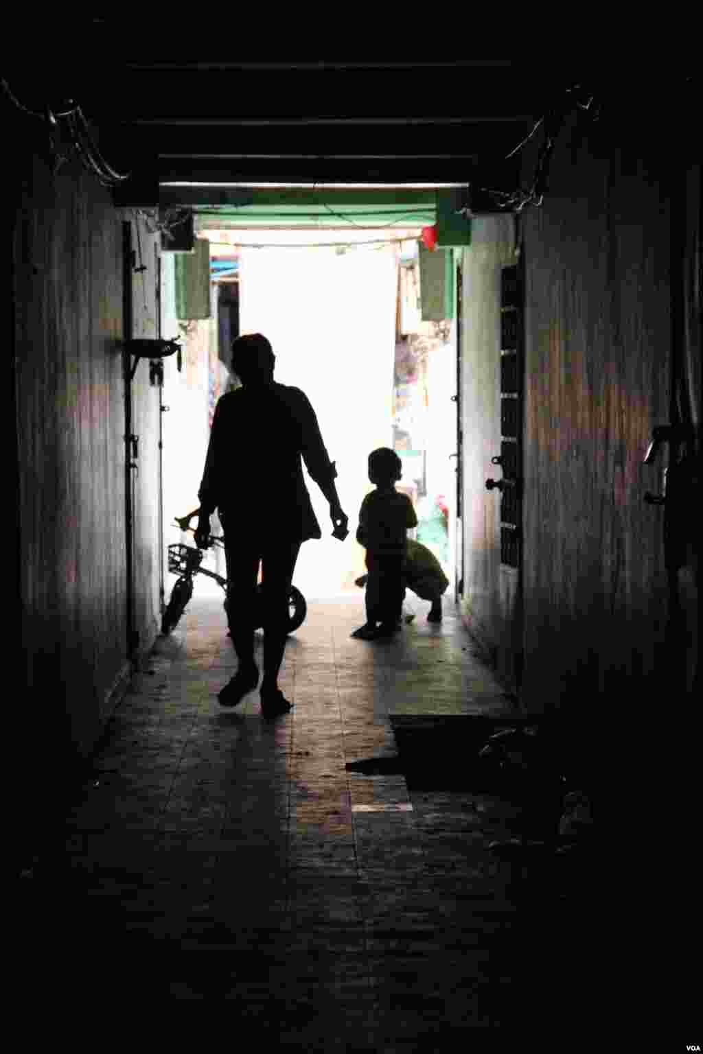 A resident and children walk through a dark corridor inside the White Building on Friday, September 5, 2014. (Nov Povleakhena/VOA Khmer)