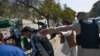 FILE - Taliban members (R) attack journalists covering a women's rights protest in Kabul on October 21, 2021.