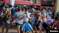 Seorang pendukung militer membawa senjata tajam saat berhadapan dengan pengunjuk rasa pro-demokrasi dalam aksi unjuk rasa di Yangon, Myanmar, 25 Februari 2021.