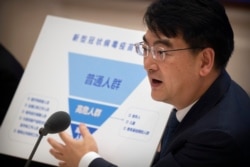 Zheng Zhongwei, from China's National Health Commission, holds a chart showing priority groups for a coronavirus vaccine as he speaks during a press conference to discuss COVID-19 vaccine-related issues on Sept. 25, 2020, in Beijing.