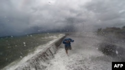 Seorang warga tengah berjalan melewati jalanan yang terkena banjir akibat gelombang besar di kota pantai Legaspi di provinsi Albay, selatan Manila (14/12).