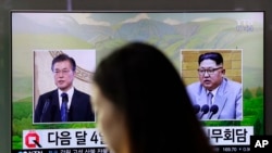 Seorang pengunjung berjalan melewati televisi yang menayangkan berita dari Presiden Korsel Moon Jae-in (kiri) dan pemimpin Korut Kim Jong-un (kanan) di stasiun kereta Seoul, Korsel, 29 Maret 2018. (Foto: dok)