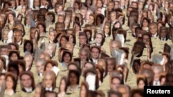 FILE - Multiple pictures of Baha'i religious leaders arrested in Iran are seen during a protest at Copacabana Beach in Rio de Janeiro, June 19, 2011.