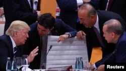 U.S. President Donald Trump, left, Turkish President Recep Tayyip Erdogan and Turkey's Foreign Minister Mevlut Cavusoglu, standing right, talk during the working session at the G20 leaders summit in Hamburg, Germany, July 7, 2017. 