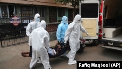 Petugas medis menjemput seorang pasien COVID-19 dari rumahnya di Mumbai, India, 28 Mei 2020.