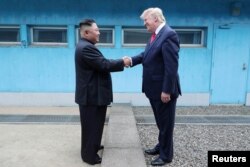 FILE - U.S. President Donald Trump shakes hands with North Korean leader Kim Jong Un as they meet at the demilitarized zone separating the two Koreas, in Panmunjom, June 30, 2019. (KCNA via Reuters)