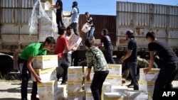 Pria-pria Suriah mengangkut kotak-kotak berisia bantuan dari Program Pangan Dunia PBB (WFP) di di al-Houla, pinggiran kota Homs sebelah utara, Suriah tengah (25/5). (AFP/Mahmoud Taha)
