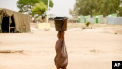 Wani yaro dauke da ruwa a bokiti a wani yankin jijar Yola da ke Najeriya (AP)