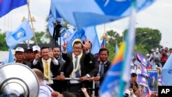 FILE: Sam Rainsy, center, president of Cambodia National Rescue Party (CNRP) greets his supporters together with his party's Vice President Kem Sokha, on Rainsy's left, on his arrival at Phnom Penh International Airport in Phnom Penh, Cambodia, Friday, July 19, 2013. Thousands of cheering supporters greeted Cambodian opposition leader Sam Rainsy as he returned from self-imposed exile Friday to spearhead his party's election campaign against well-entrenched Prime Minister Hun Sen. (AP Photo/Heng Sinith)