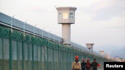 Para pekerja berjalan di dekat pagar pembatas dari suatu tempat yang secara resmi dikenal sebagai pusat pendidikan keterampilan kejuruan di Dabancheng di Daerah Otonomi Uighur Xinjiang, China, 4 September 2018. (Foto: Reuters)