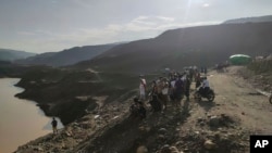 Para penambang, petugas SAR dan warga setempat memperhatikan di tambang batu giok, yang juga lokasi tanah longsor di Hpakant, negara bagian Kachin, Myanmar, Minggu, 13 Agustus 2023. (Foto: AP Photo)