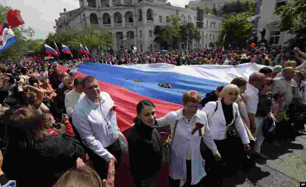Local residents carry a giant Russian flag as they march through the city after the Victory Day military parade, which commemorates the 1945 defeat of Nazi Germany, in Sevastopol, Russia, May 9, 2014.