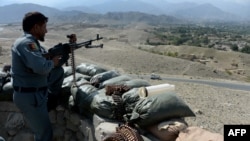 FILE - An Afghan security force member stands at a checkpoint, set alight by Islamic State fighters during overnight clashes, in the Achin district of eastern Nangarhar province, Sept. 28, 2015.