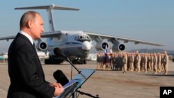 Presiden Vladimir Putin berpidato dihadapan pasukan Rusia di pangkalan udara Hemeimeem, di Suriah, 11 Desember 2017.