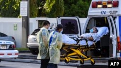 Petugas medis memindahkan pasien dengan tandu dari ambulans di luar Gawat Darurat di Rumah Sakit Coral Gables tempat pasien virus corona dirawat di Coral Gables dekat Miami, pada 30 Juli 2020. (Foto: AFP)
