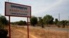 A man rides a motorcycle past a signboard for the Cambodia Iron Group at the Rovieng District in Preah Vihear province, February 10, 2013.
