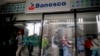 Un cliente sale de una sucursal bancaria de Banesco mientras otros hacen fila, en Caracas, Venezuela, el viernes 4 de mayo de 2018.