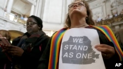 Pastor Annie Steinberg-Behrman (kanan) dari Gereja Metropolitan Community, memegang kertas pernyataan dukungan saat menghadiri rapat di Balai Kota San Francisco untuk menekankan lagi komitmen kota itu sebagai kota perlindungan, November 2016. (AP/Jeff Chiu)