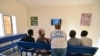 Seorang petugas UNHCR (tengah) berbicara dengan para pengungsi sembari menonton televisi di ruang tunggu kantor UNHCR di Niamey, Niger, 17 November 2017. Para pengungsi dievakuasi dari Libya. 