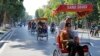 坐在三轮人力车上观赏河内街景的中国游客。
