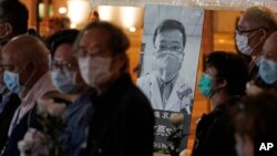 People wearing masks, attend a vigil for Chinese doctor Li Wenliang, in Hong Kong, Friday, Feb. 7, 2020. 
