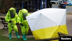 FILE - The forensic tent, covering the bench where Sergei Skripal and his daughter Yulia were found, is repositioned by officials in protective suits in the center of Salisbury, Britain, March 8, 2018.