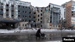 Seorang perempuan melewati gedung yang rusak akibat serangan militer Rusia di tengah serangan Rusia terhadap Ukraina di Kota Pokrovsk di wilayah Donetsk, Ukraina, Kamis, 12 Desember 2024. (Foto: Inna Varenytsia/Reuters)