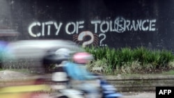 Seorang pengendara mobil melewati grafiti menyerukan toleransi di Yogyakarta, 8 Mei 2016. (Foto: AFP)